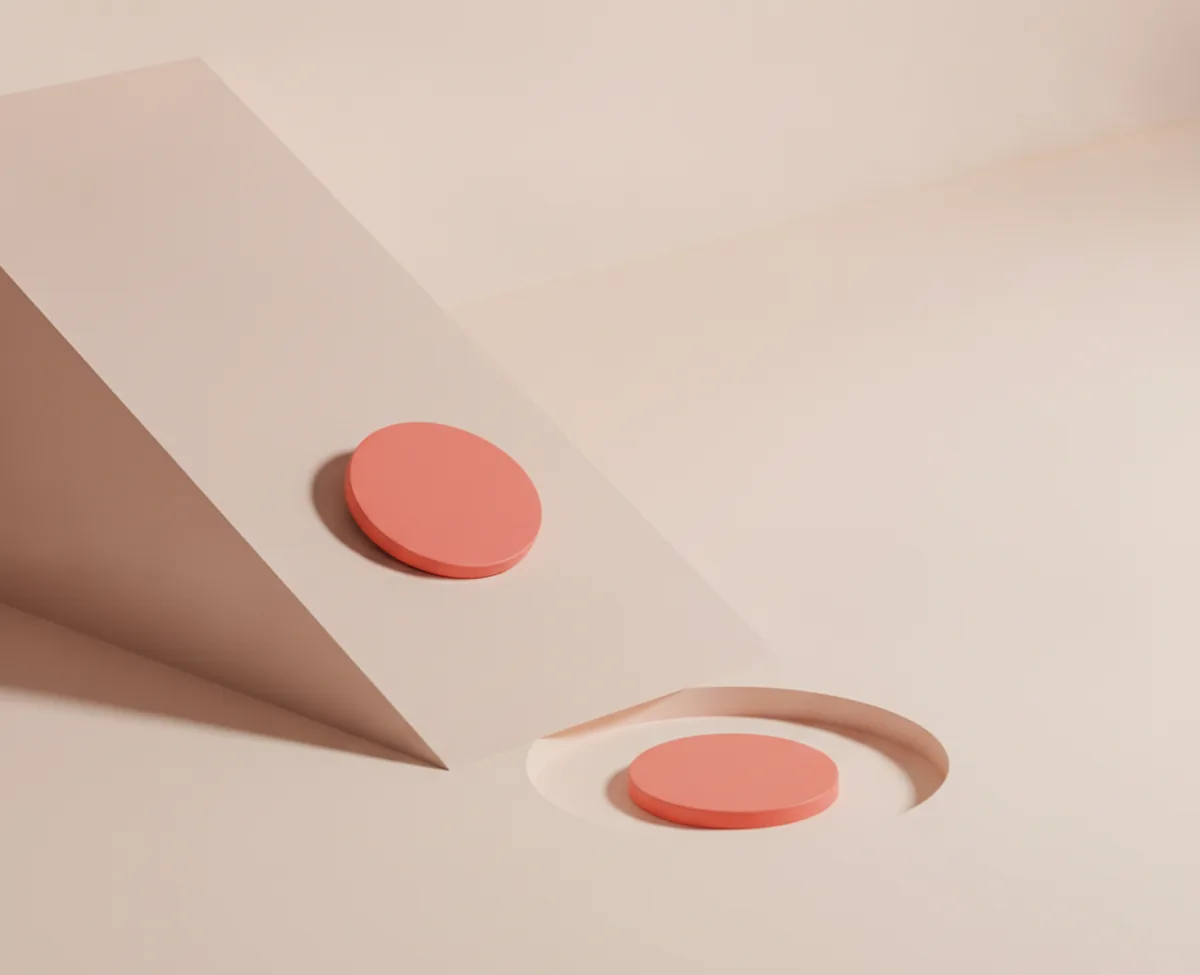 A pale ramp descending to a shallow dish set into a warm floor, one coral disc part-way down the ramp and a second already resting in the dish