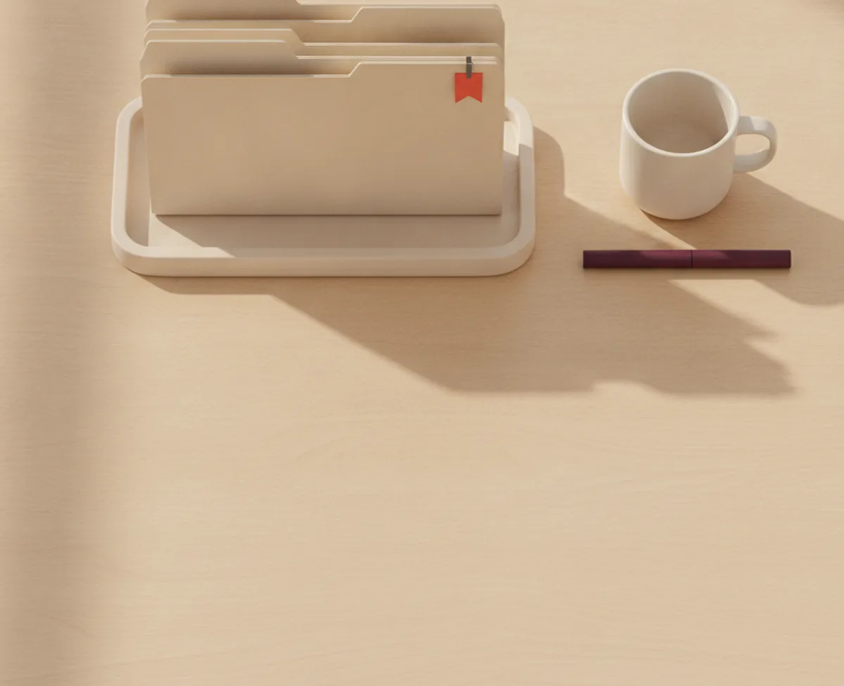 An overhead of a desk tray with manila folders standing upright, the front folder pushed forward and carrying a small coral flag on its top edge